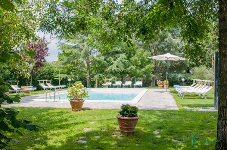 La piscina con il solarium dotato di ombrelloni, sedie e lettini