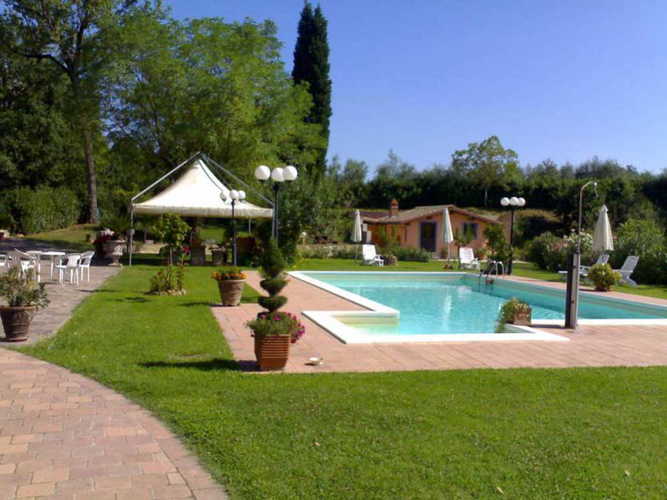 La piscina con la zona solarium, ombrelloni, sdraio e gazebo