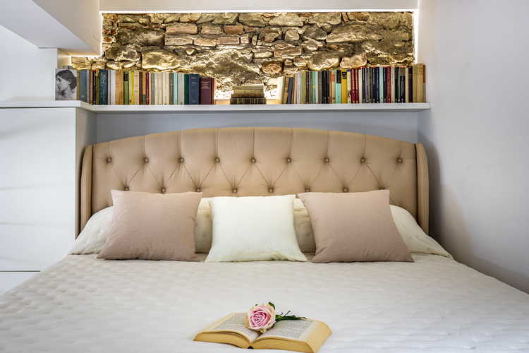 Il letto matrimoniale ubicato sul soppalco a vista e circondato dai libri da cui prende il nome l'appartamento