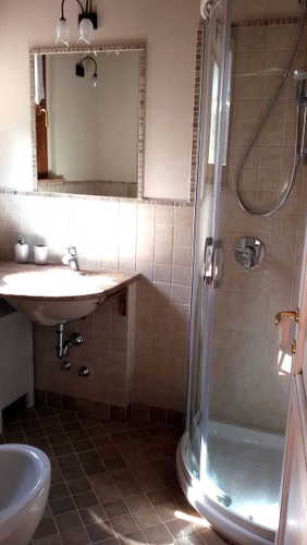 Bagno con doccia dall'arredo moderno e colori tenui