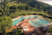 View from above of the two pools surrounded by the green of the hillside on which Borgo La Casaccia sits